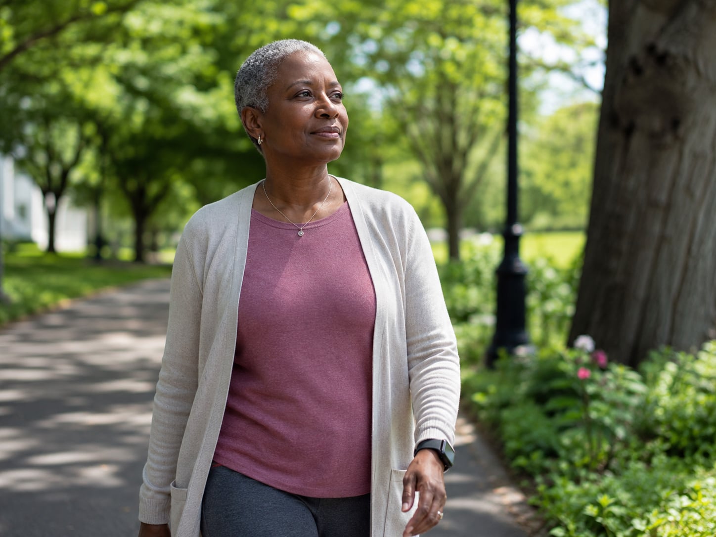 A woman in headscarf walks alone along a tree-lined park path