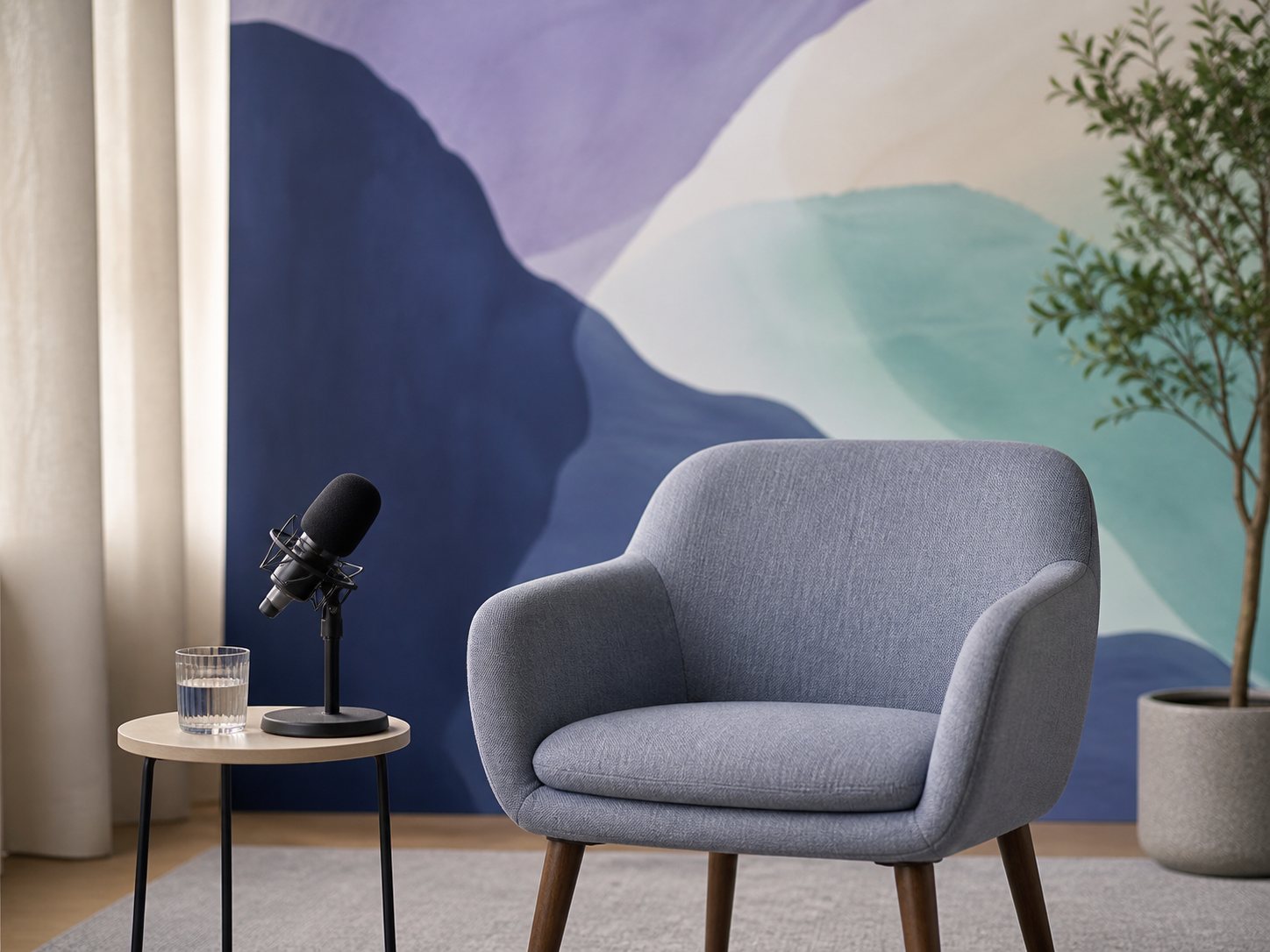 An empty armchair with a broadcast microphone on a side table against an abstract mural.