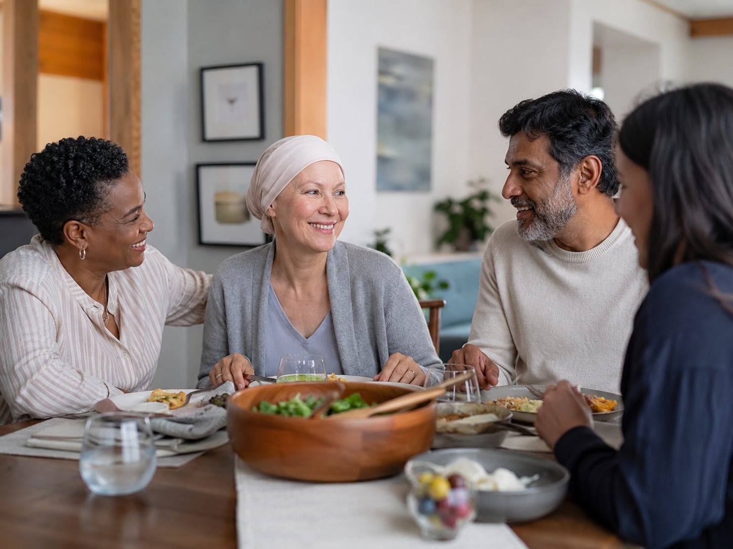Four people share a meal together at a table, smiling