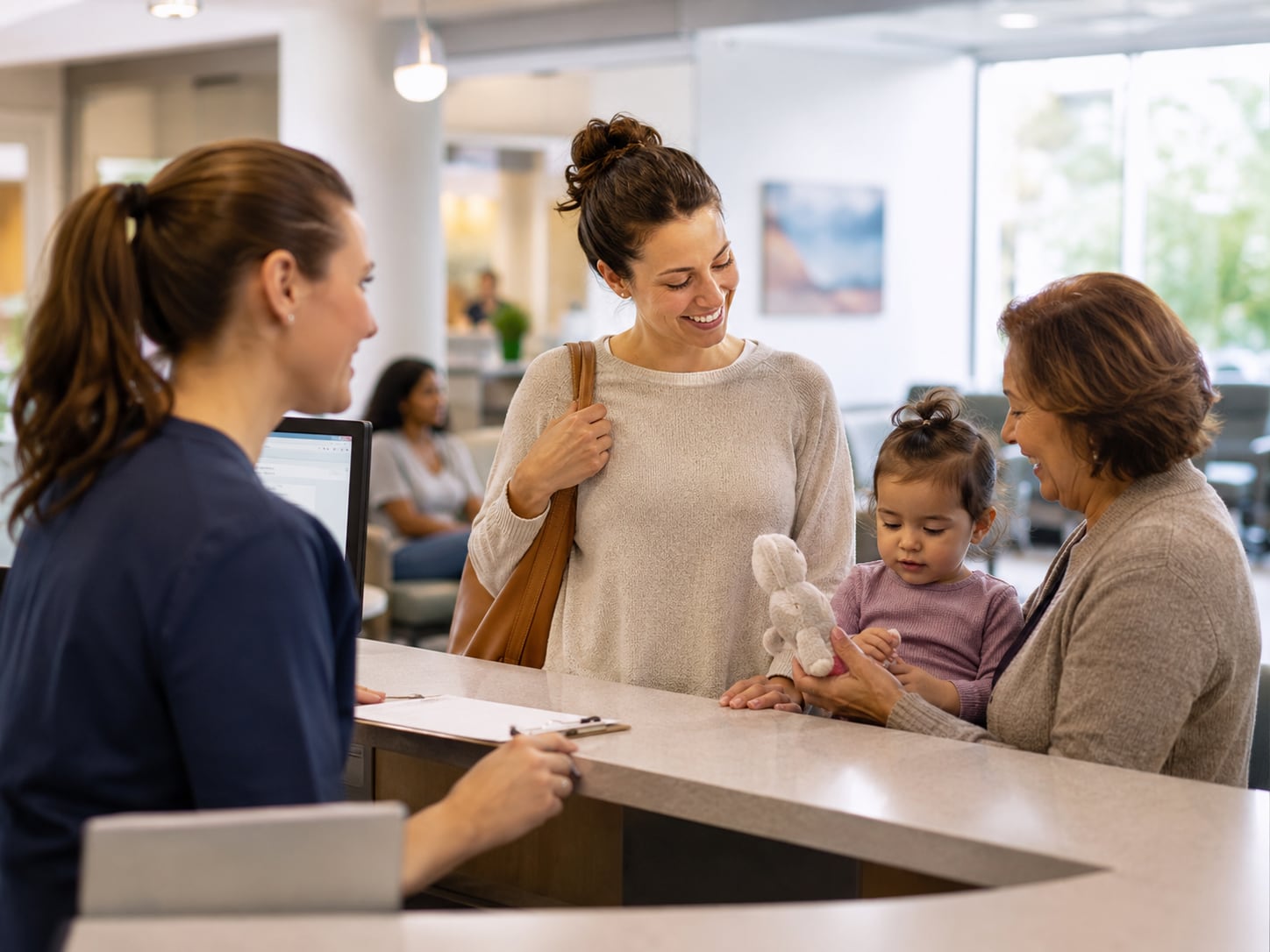 A woman and young child at desk while older woman looks on in waiting area