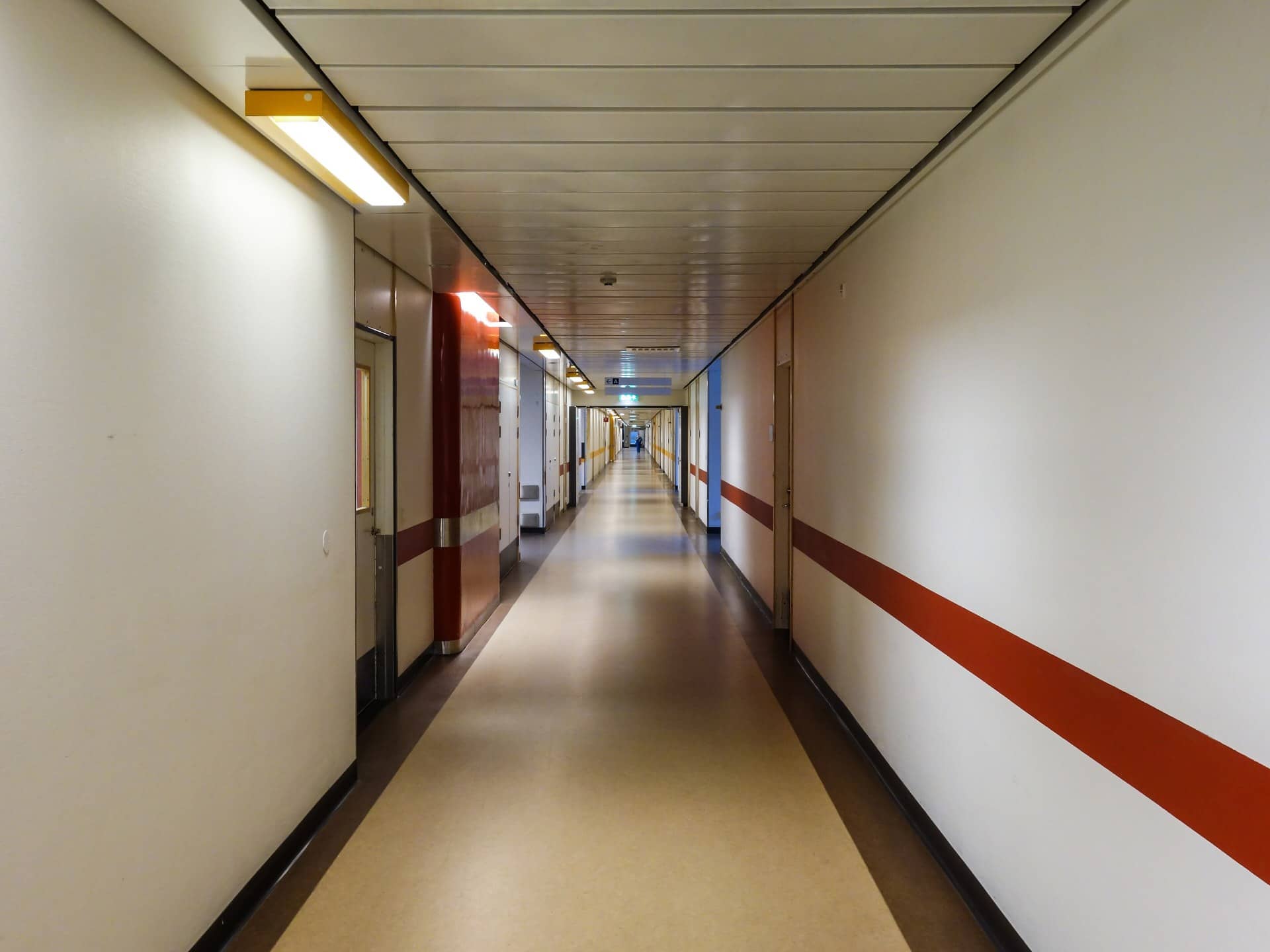 A long, empty indoor corridor with a red stripe along the wall.