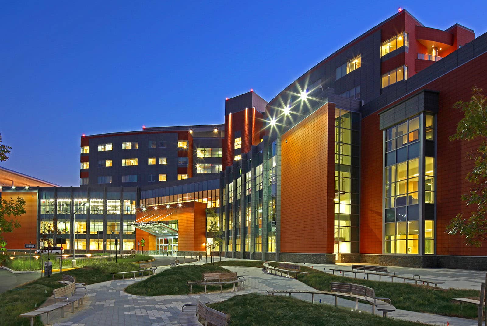 A large modern building with lit windows against a deep blue evening sky.