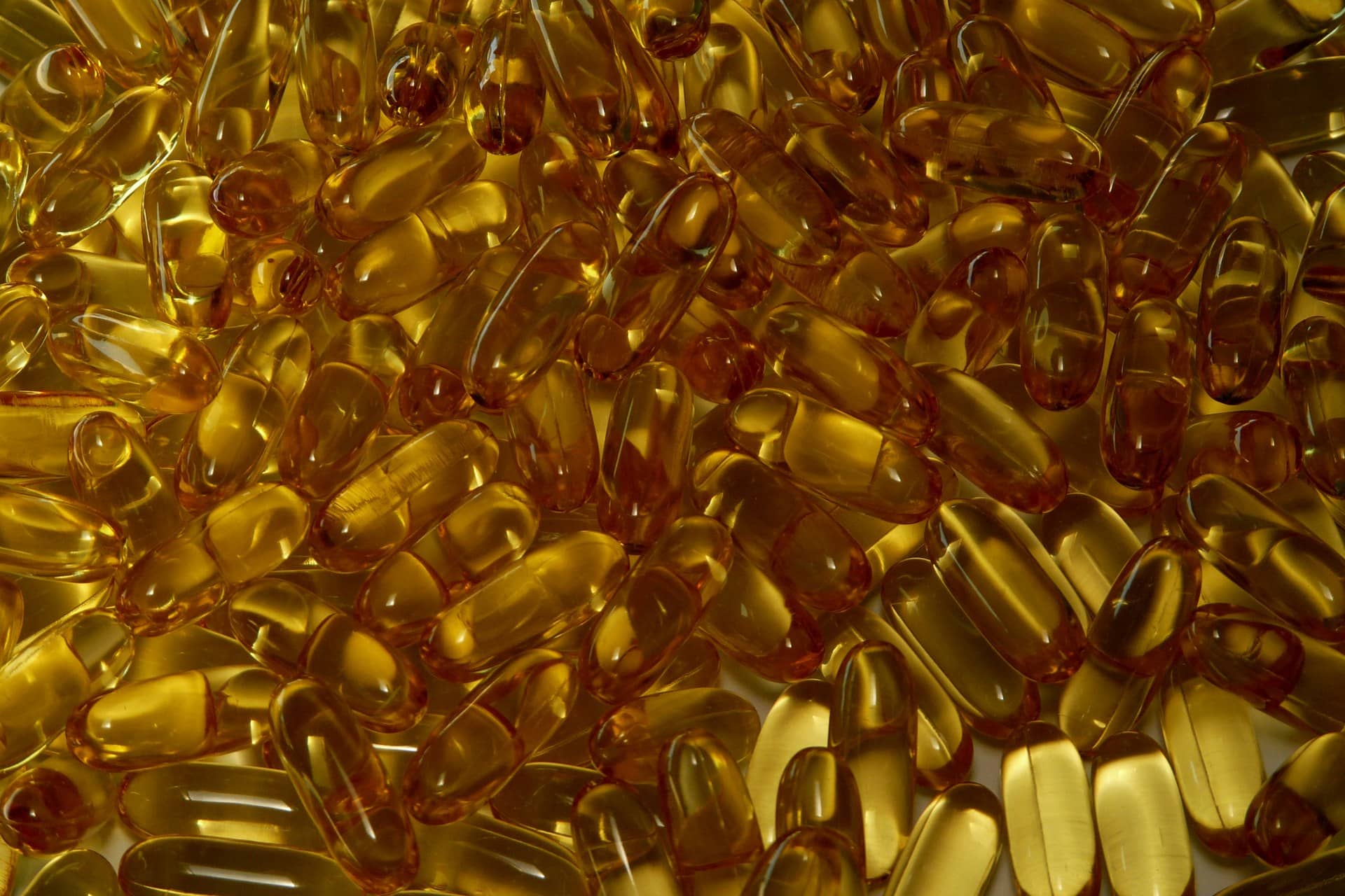 Dense close view of translucent golden softgel capsules.
