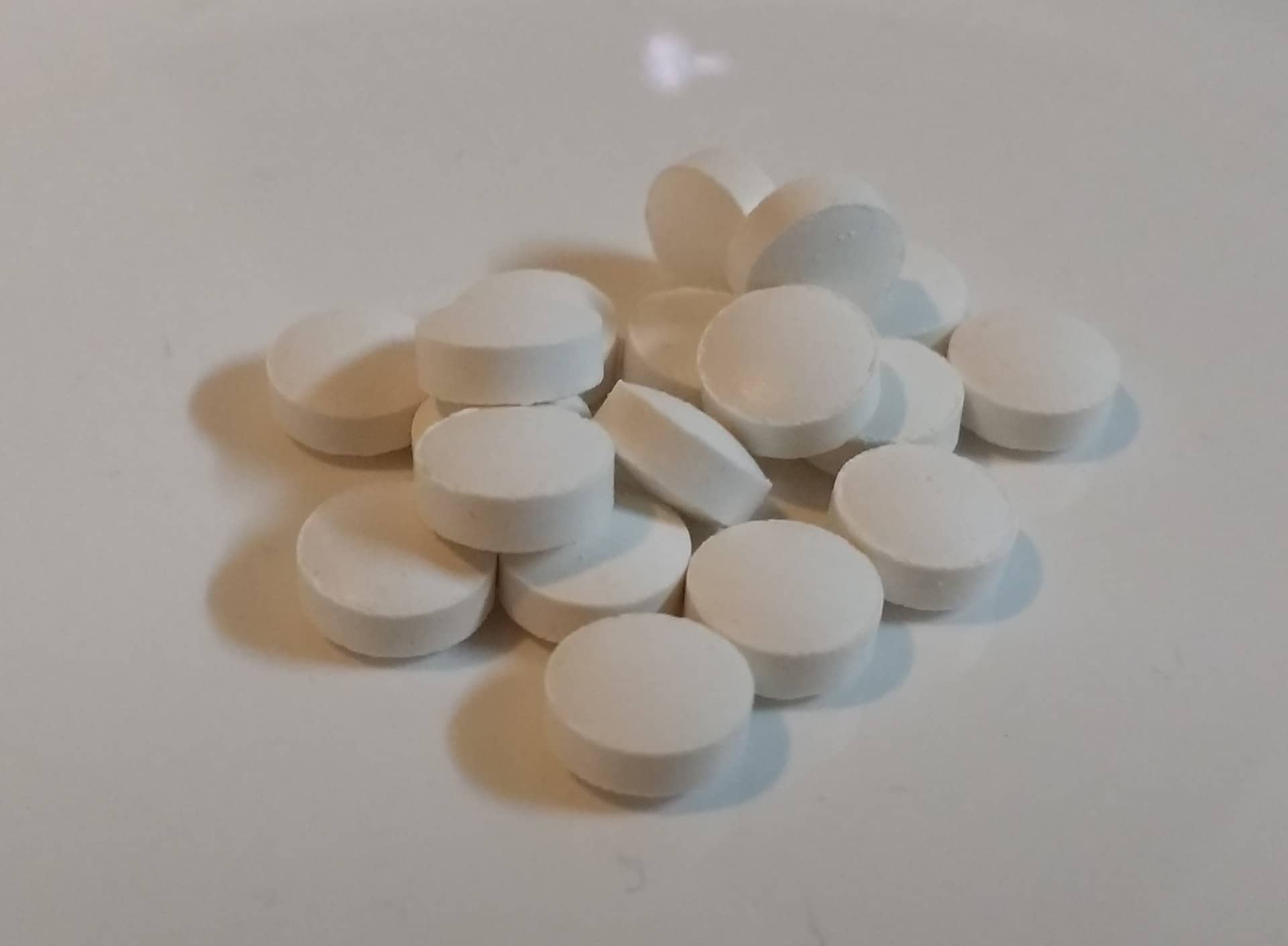 A small cluster of round white tablets on a pale surface.