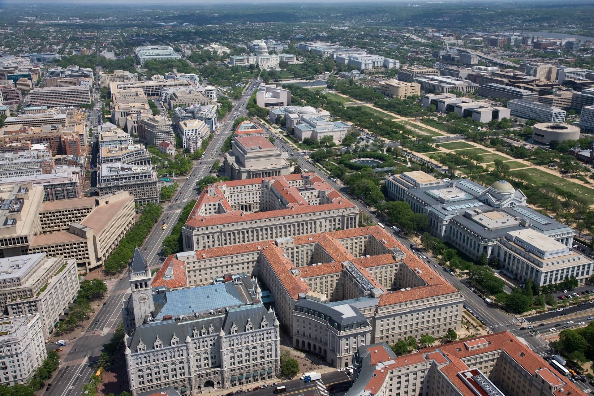 Aerial view of large government office buildings with red tile roofs and a city beyond.
