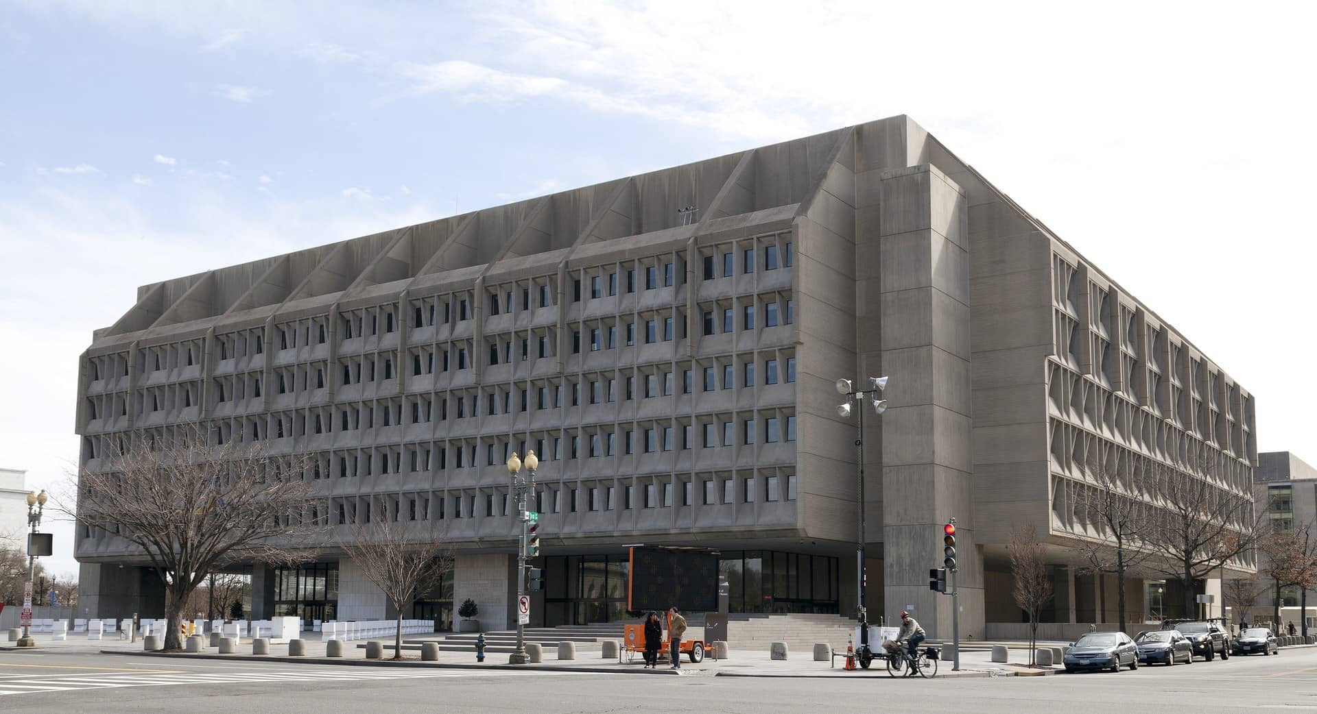 Large concrete government office building on a street corner under a pale sky.