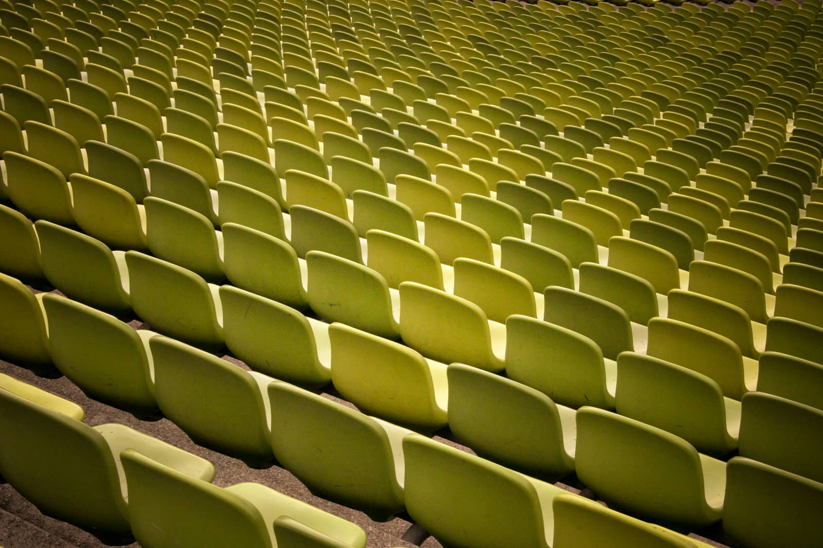Many rows of empty yellow-green stadium seats.