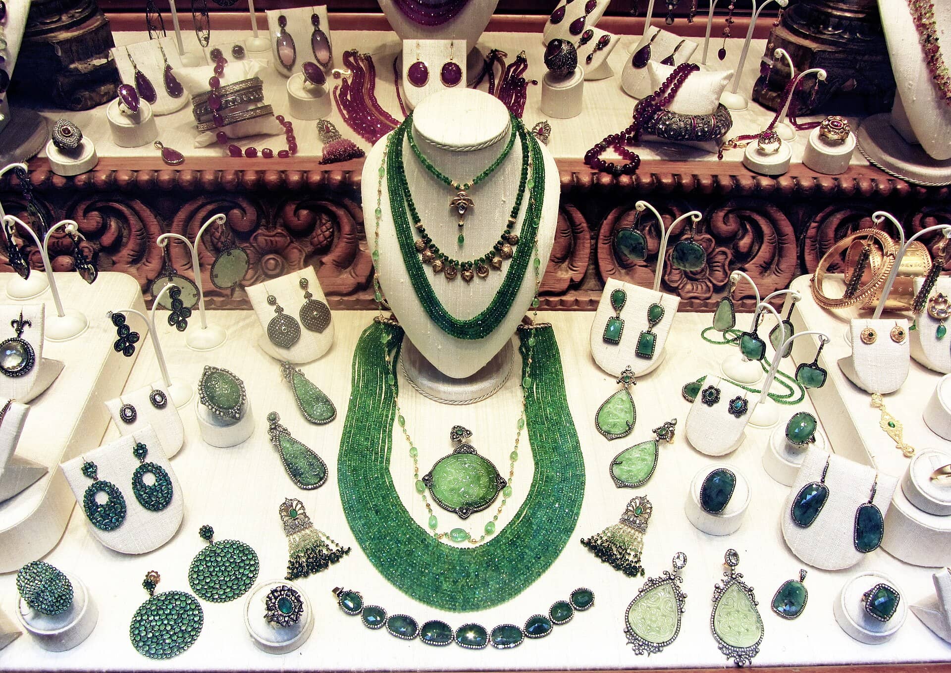 A shop display of green bead necklaces, earrings and rings on white stands.
