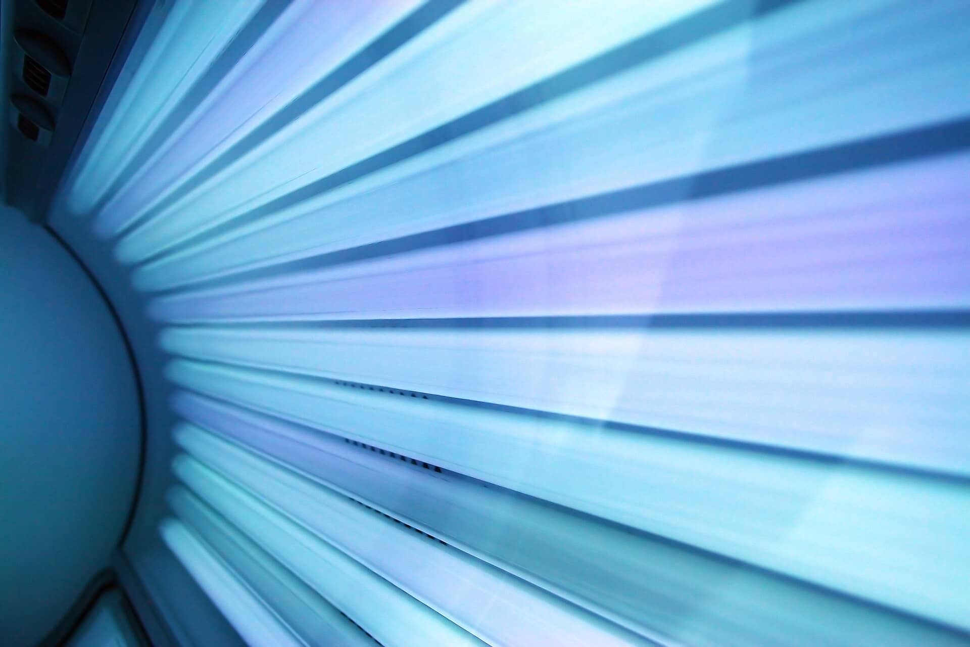 Close view of bright blue-white lamps lining the inside of a tanning bed.