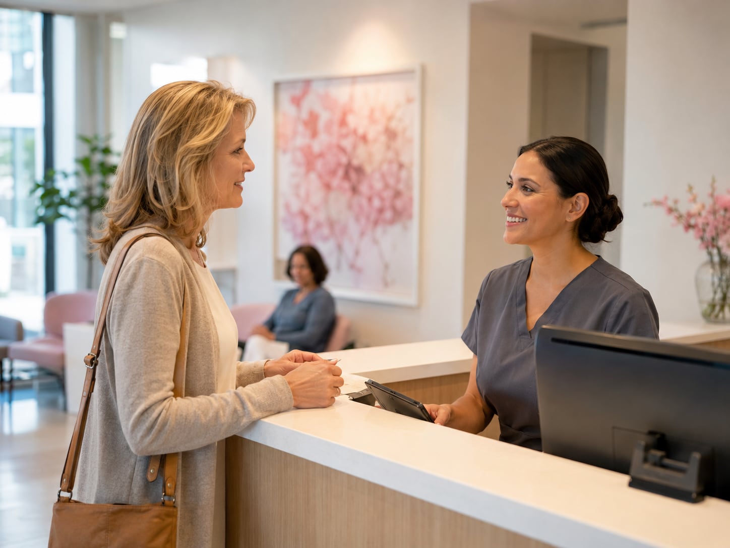 A woman talks with a clinician at a reception desk in a clinic lobby